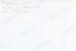 O verso de uma fotografia Kodak contendo uma anotação manuscrita a lápis sobre uma exposição de artes plásticas realizada no hall da prefeitura. O texto sugere um registro documental de um evento cultural local, possivelmente ocorrido na segunda metade do século XX.
