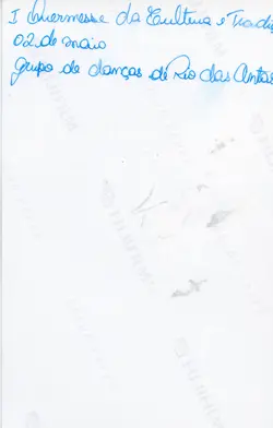 O verso de uma fotografia com anotações manuscritas em tinta azul, identificando um evento cultural. O texto menciona a 'I Quermesse da Cultura e Tradição' realizada em 2 de maio, envolvendo o grupo de danças de Rio das Antas.