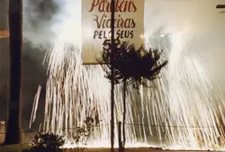 Uma fotografia noturna capturando uma celebração com fogos de artifício em Videira, Santa Catarina. O cartaz comemorativo parabeniza os 'Videirenses' pelo aniversário de 52 anos da cidade, sugerindo um evento cívico ou festivo ocorrido em 1996.