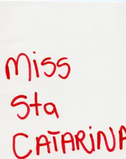 Uma imagem contendo a inscrição manuscrita em tinta vermelha 'Miss Sta Catarina' sobre um fundo branco. O texto provavelmente refere-se a um concurso de beleza estadual, possivelmente utilizado como cartaz ou identificação em algum evento social.
