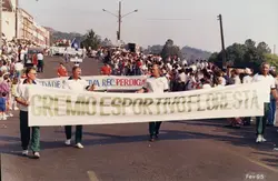 Uma fotografia de um desfile ou evento público em uma rua, onde homens carregam uma faixa do Grêmio Esportivo Floresta. O contexto sugere uma celebração comunitária ou esportiva em uma cidade brasileira, com a presença de público nas calçadas e veículos ao fundo, datada de fevereiro de 1995.