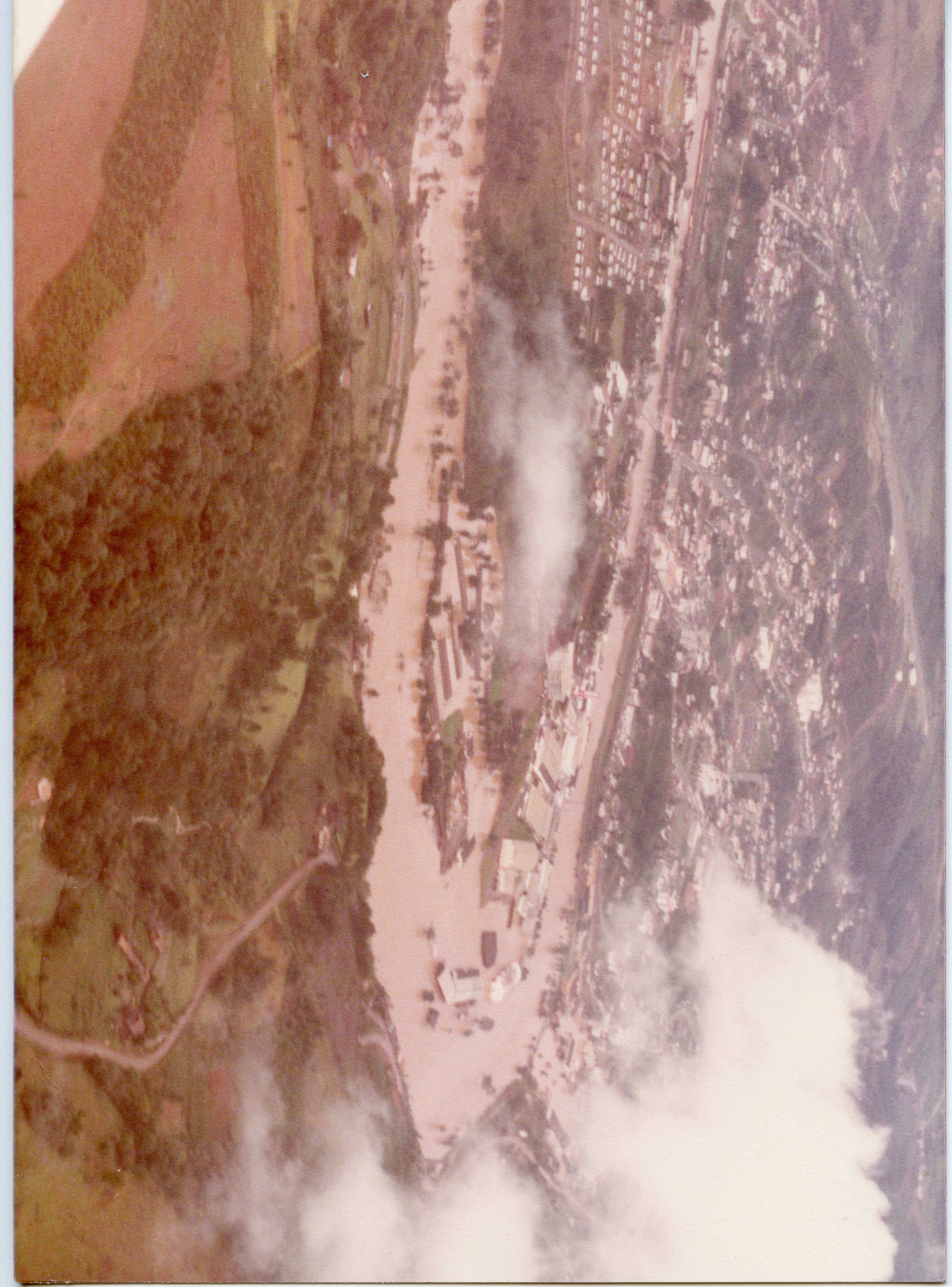 Uma fotografia aérea de uma enchente em uma área urbana, possivelmente em uma cidade do interior brasileiro. A imagem mostra um rio transbordado ocupando grande parte do vale, com construções próximas à margem submersas ou isoladas, sugerindo um evento climático severo de meados do século XX.