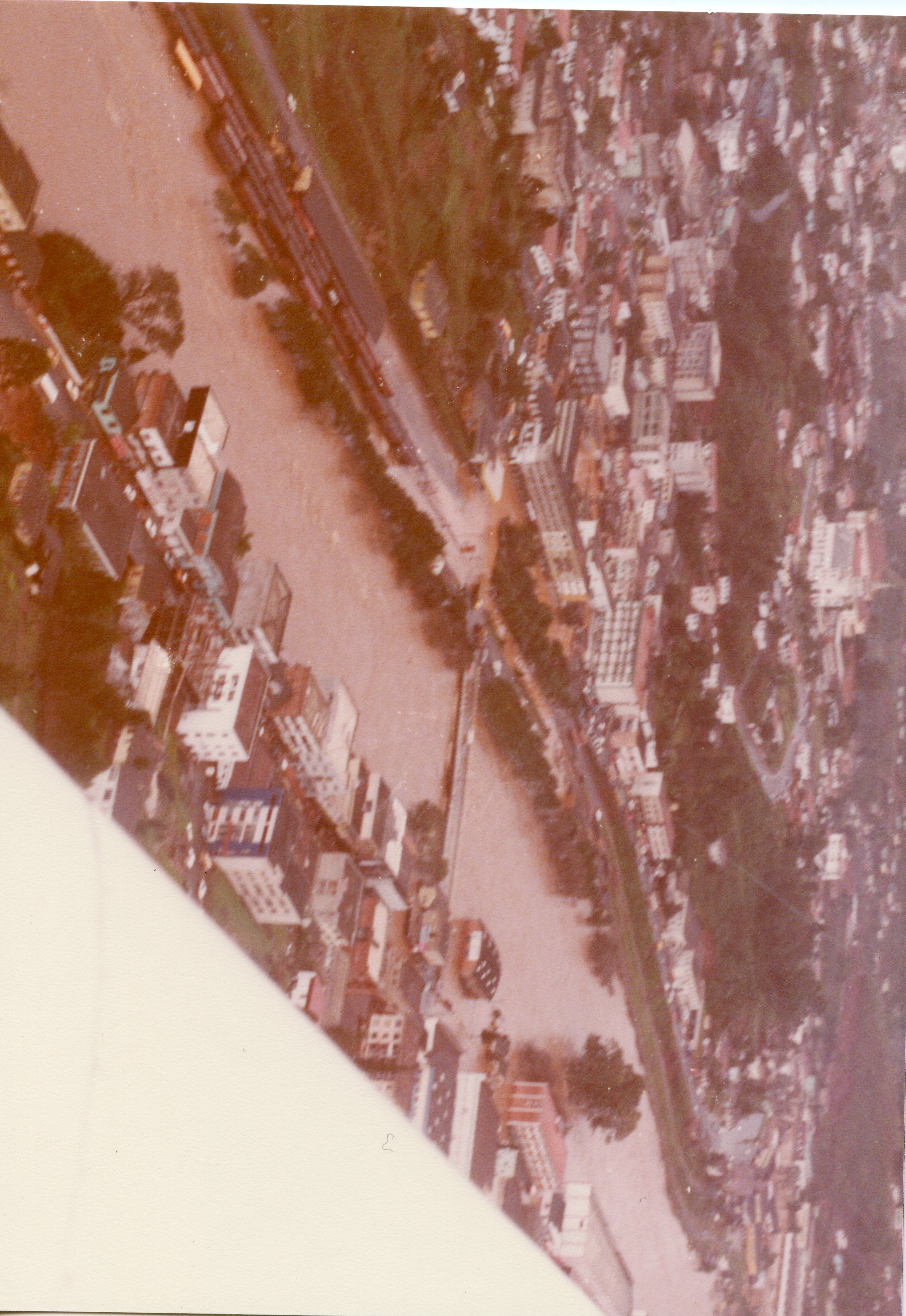 Uma fotografia aérea de uma cidade, possivelmente Videira, mostrando um rio com águas barrentas que parece ter transbordado ou atingido um nível elevado. A imagem apresenta uma perspectiva urbana com edifícios e ruas, sugerindo um evento de enchente ocorrido provavelmente entre as décadas de 1970 e 1980.