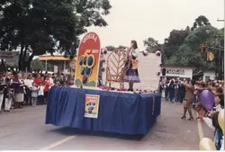 Fotografia de um desfile comemorativo em Videira, celebrando os 50 anos da cidade. O carro alegórico exibe o logotipo do cinquentenário e uma pessoa vestida com trajes típicos, em um contexto de celebração pública ao ar livre.
