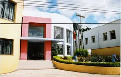 Fotografia colorida de um edifício comercial moderno com fachada pintada em tons de amarelo, branco e rosa, localizado em uma área urbana. O letreiro indica 'Centro de Eventos Videira', sugerindo um espaço público ou cultural na cidade de Videira, Santa Catarina.