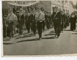 Fotografia em preto e branco de um desfile cívico, provavelmente em uma cidade brasileira, com jovens marchando e carregando uma faixa com os dizeres 'Independência ou Morte'. A cena inclui uma freira e estudantes uniformizados, sugerindo um evento escolar ou comemorativo de meados do século XX.