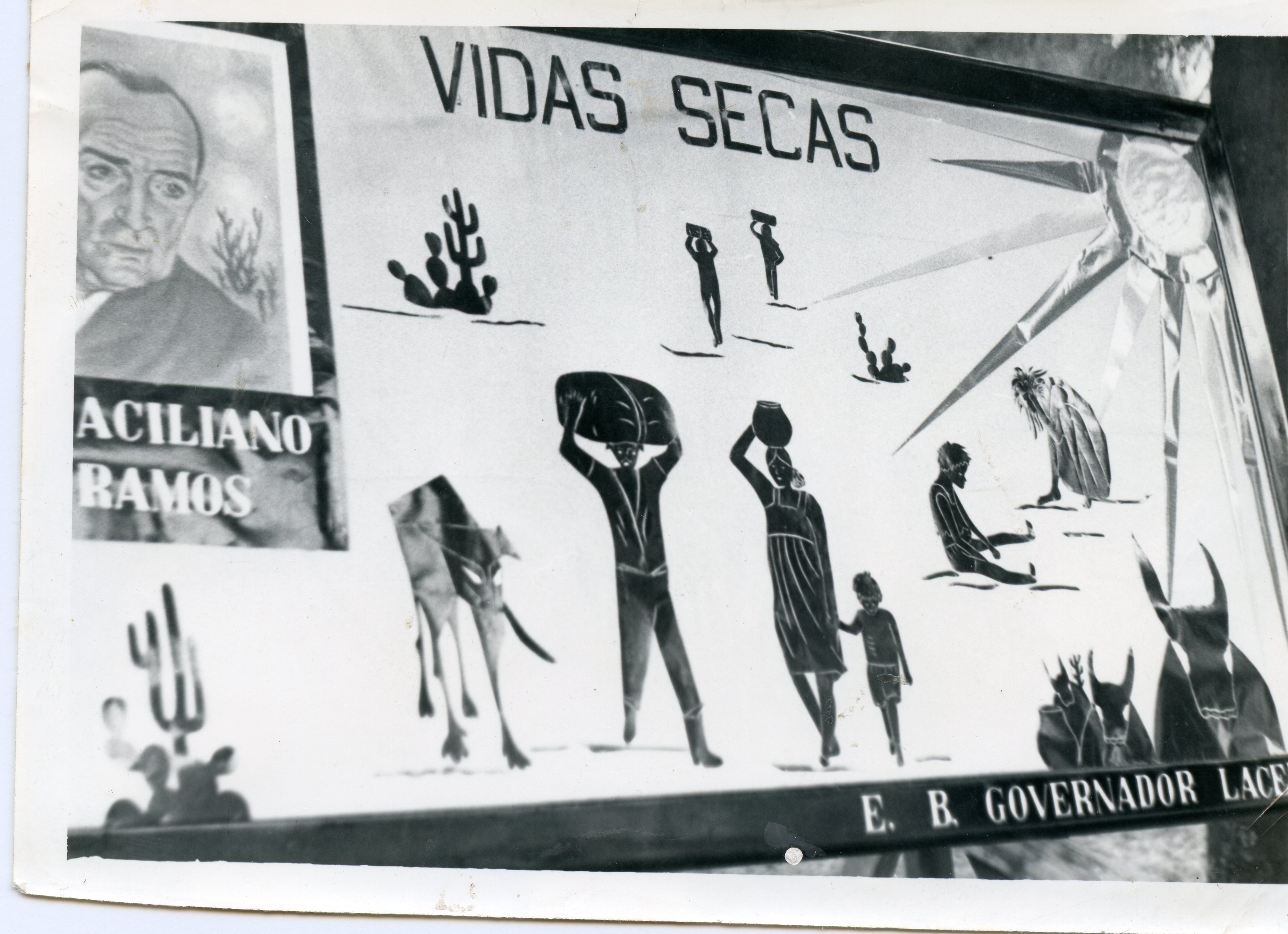 Uma fotografia em preto e branco de um cartaz ou painel escolar ilustrando a obra 'Vidas Secas' de Graciliano Ramos. O painel apresenta desenhos estilizados de uma família retirante, cactos e um sol forte, típicos do cenário da seca no sertão brasileiro, com o retrato do autor no canto superior esquerdo.