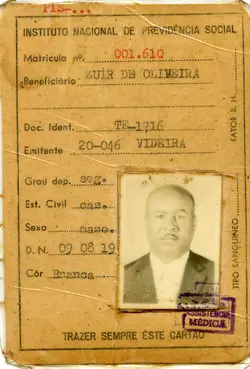 Este é um cartão de identificação do Instituto Nacional de Previdência Social, emitido em Videira. O documento contém informações pessoais como nome, matrícula, documento de identidade, data de nascimento e tipo sanguíneo, além de uma fotografia do beneficiário. O estado de conservação sugere que seja um documento antigo, possivelmente da segunda metade do século XX.