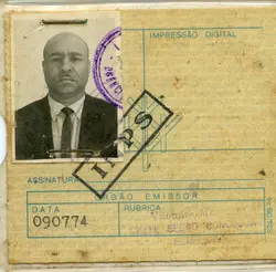 Este é um documento de identificação com uma fotografia em preto e branco de um homem vestindo terno e gravata. O documento parece ser antigo, com marcas de uso e carimbos. Há texto em português e um número de identificação visível. O contexto é provavelmente um documento oficial brasileiro.