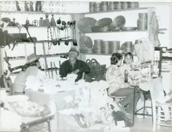 Uma fotografia em preto e branco que retrata uma feira de artesanato ou exposição cultural, possivelmente em uma cidade do interior brasileiro. Vê-se pessoas sentadas em estandes com prateleiras repletas de cestarias, objetos de madeira e itens decorativos, sugerindo um evento comunitário ou de valorização da cultura local, provavelmente datado entre as décadas de 1970 e 1980.
