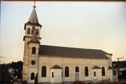 Fotografia de uma igreja católica de arquitetura clássica com torre sineira, típica de cidades do interior do sul do Brasil. A imagem apresenta uma estrutura bem preservada, sugerindo um registro de meados do século XX, possivelmente em um contexto de colonização europeia.
