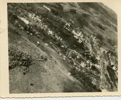 Fotografia aérea em preto e branco de uma pequena cidade brasileira, possivelmente em fase inicial de desenvolvimento urbano. A imagem destaca a disposição das construções ao longo de uma via principal, com áreas rurais e vegetação circundante, sugerindo um registro histórico de meados do século XX.