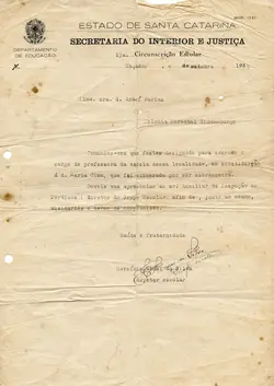 Documento oficial datilografado da Secretaria do Interior e Justiça de Santa Catarina, datado de 1939, comunicando a nomeação de uma professora em Caçador. O texto menciona a exoneração de uma professora estrangeira, refletindo o contexto político da época, e apresenta marcas de dobras e manchas de envelhecimento típicas de papéis históricos.