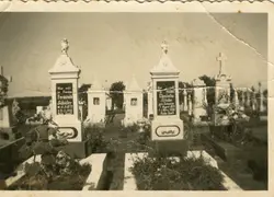 Fotografia em preto e branco de um cemitério com lápides de estilo europeu, contendo inscrições em alemão. A imagem sugere um contexto de imigração, possivelmente em uma comunidade rural do sul do Brasil, datada provavelmente de meados do século XX.
