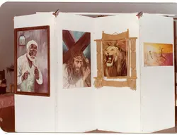 Uma exposição de arte organizada em painéis brancos modulares, exibindo pinturas com temas religiosos e da natureza. A cena sugere um evento cultural ou exposição comunitária, possivelmente ocorrida entre as décadas de 1980 e 1990, dado o estilo das molduras e a técnica fotográfica.